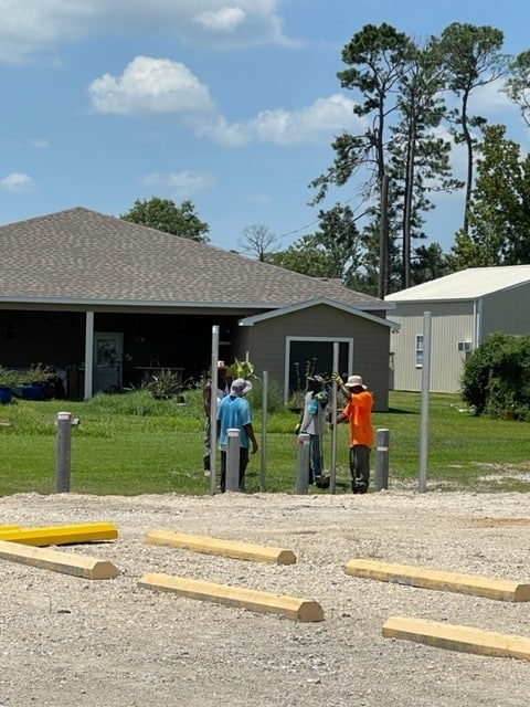 Workers building new 6-foot fence at drainage ditch opening at far west portion of parking lot