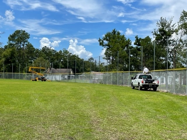 Workers install tall nets in outfield of field 11